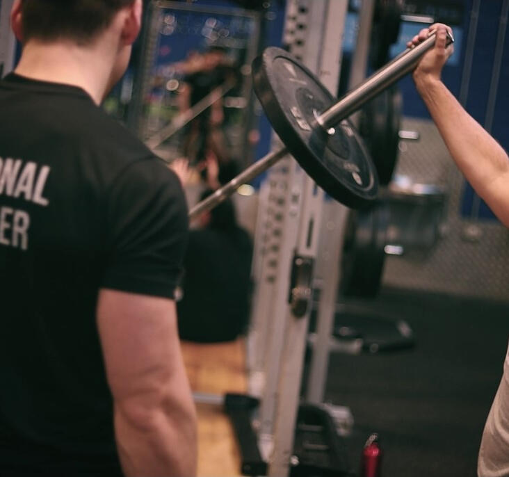 Personal Trainer and client at Flyefit Markus coaching and client performing a half-kneeling landmine press